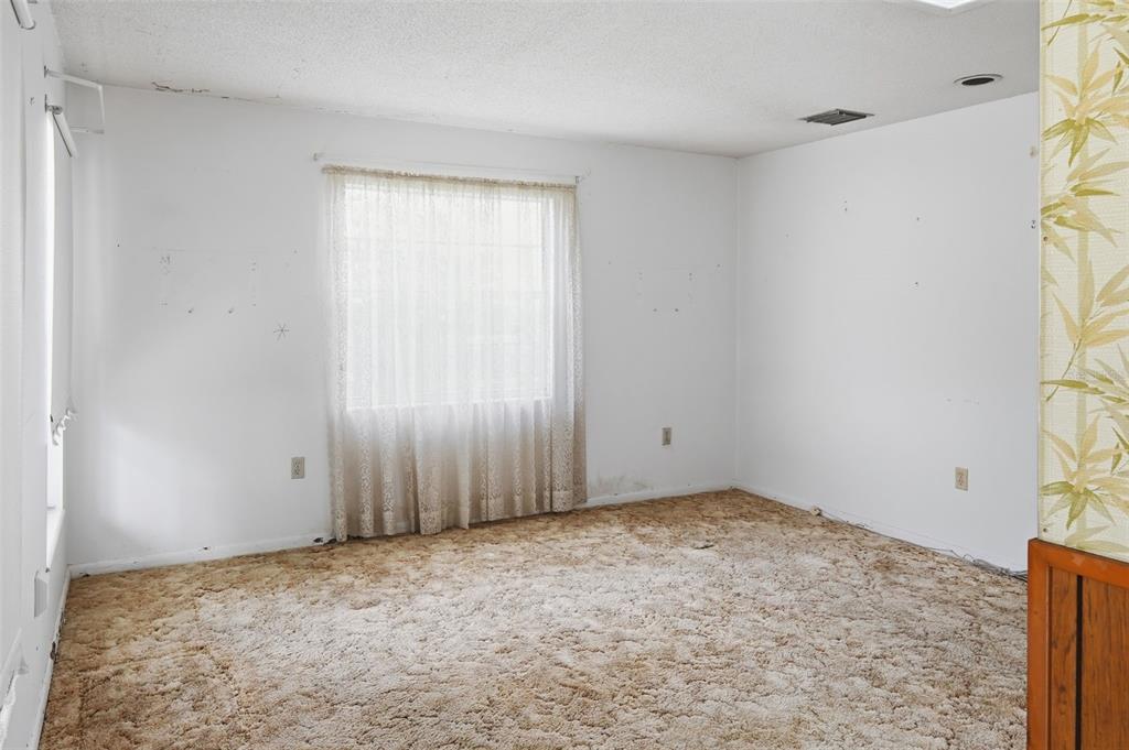 An empty bedroom with white walls, beige carpet, and a window with lace curtains — 1013 SUNWOOD LANE, ORLANDO, FL