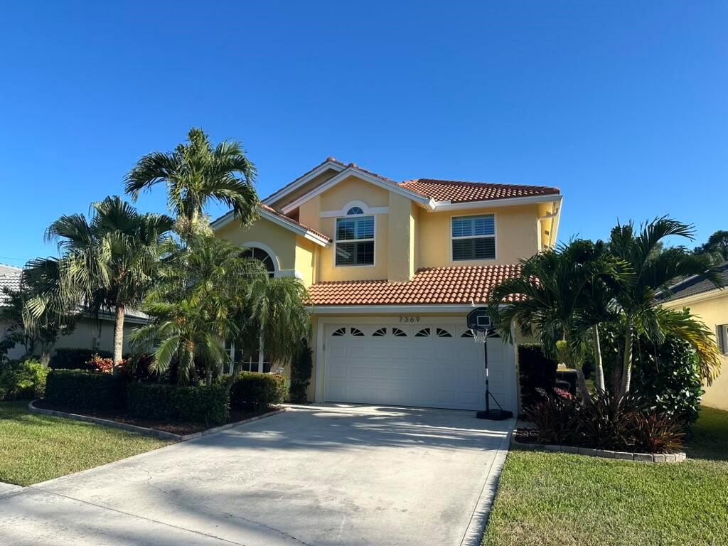 A two-story yellow house with a tile roof and a two-car garage — 7369 SE Seagate Lane, Stuart FL 34997, STUART, FL