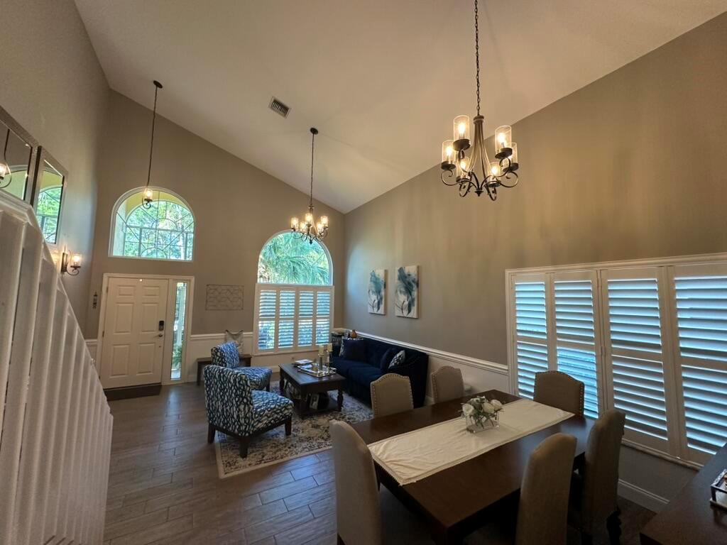 A high-ceilinged dining and living area features tile floors, arched windows, and two chandeliers — 7369 SE Seagate Lane, Stuart FL 34997, STUART, FL