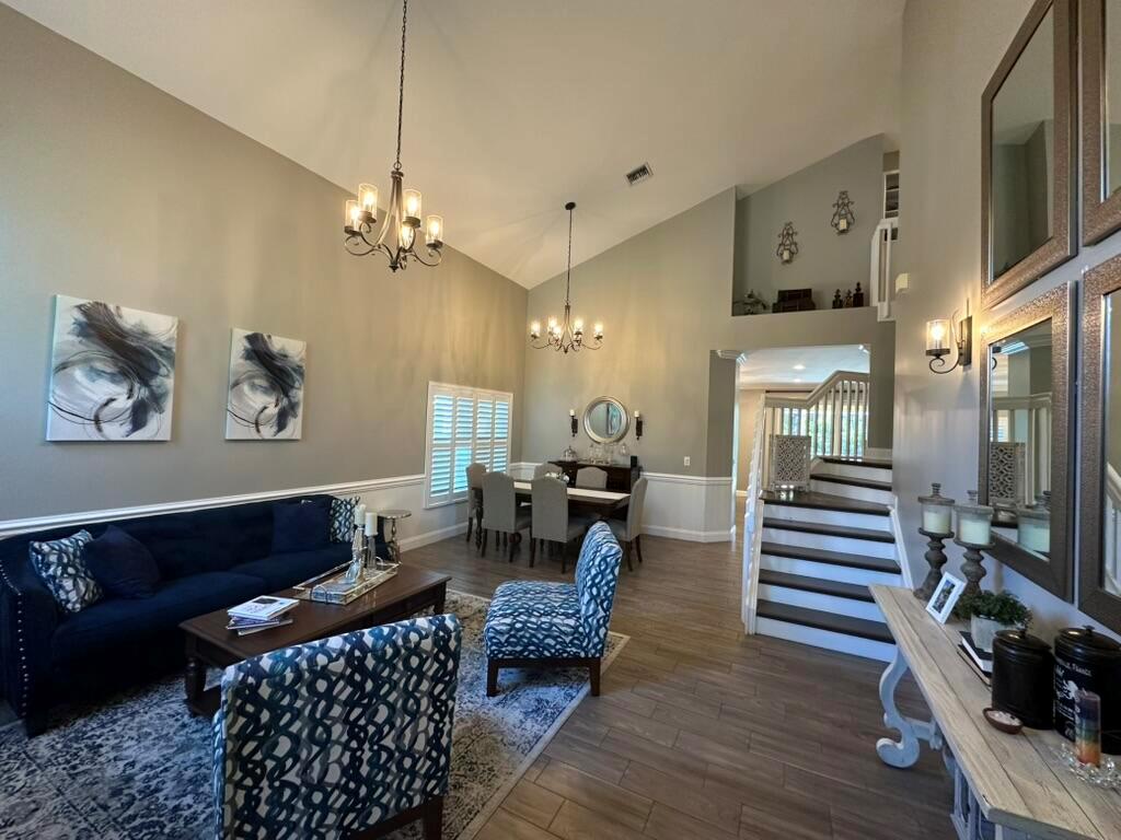 A living and dining area with vaulted ceilings, a blue sofa, and a staircase — 7369 SE Seagate Lane, Stuart FL 34997, STUART, FL