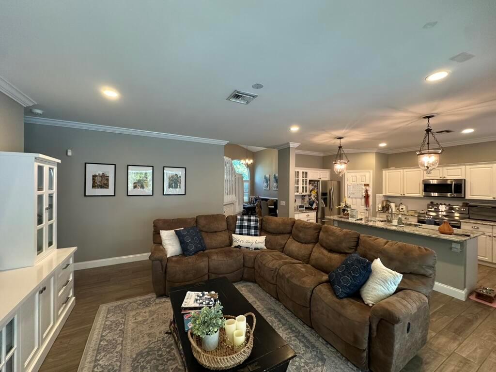 A living room with a brown sectional sofa, coffee table, and an open-concept kitchen — 7369 SE Seagate Lane, Stuart FL 34997, STUART, FL