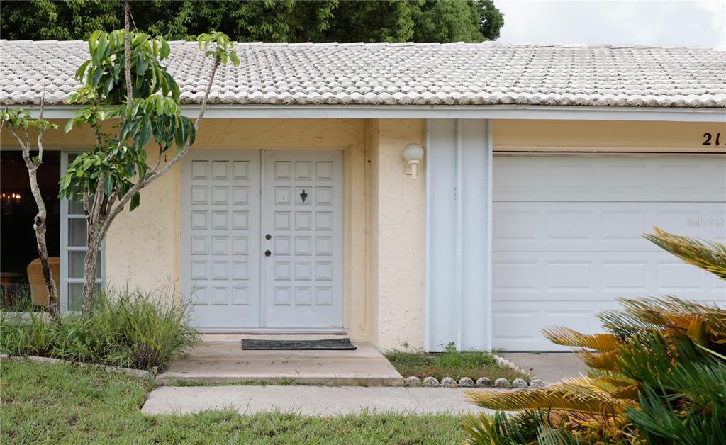 The exterior of a single-story house features a double front door, garage, and tiled roof — 2132 PORTSIDE PASSAGE, PALM HARBOR, FL