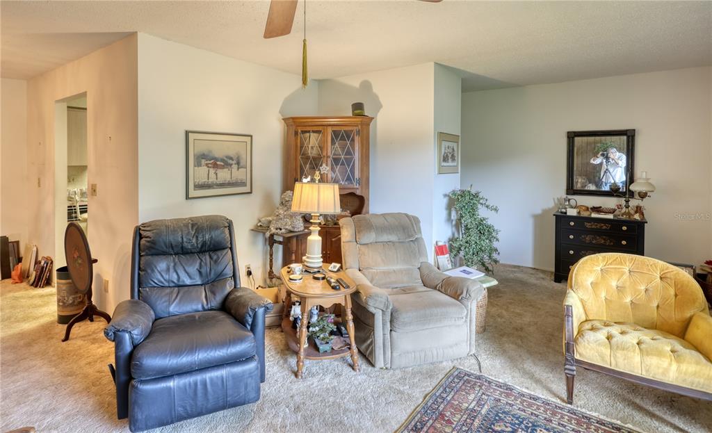 A dining area with wood-paneled walls opens into a living room and a bedroom — 2132 PORTSIDE PASSAGE, PALM HARBOR, FL