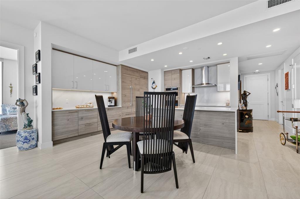 A modern kitchen and dining area features wood-grain cabinetry, white upper cabinets, and a round table — 301 1ST STREET S UNIT 1505, ST PETERSBURG, FL