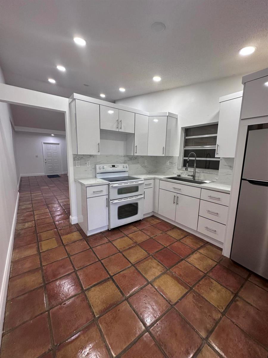 A kitchen with white cabinets, stainless steel appliances, and terracotta tile flooring — 19823 NW 64th Place, Hialeah FL 33015, HIALEAH, FL