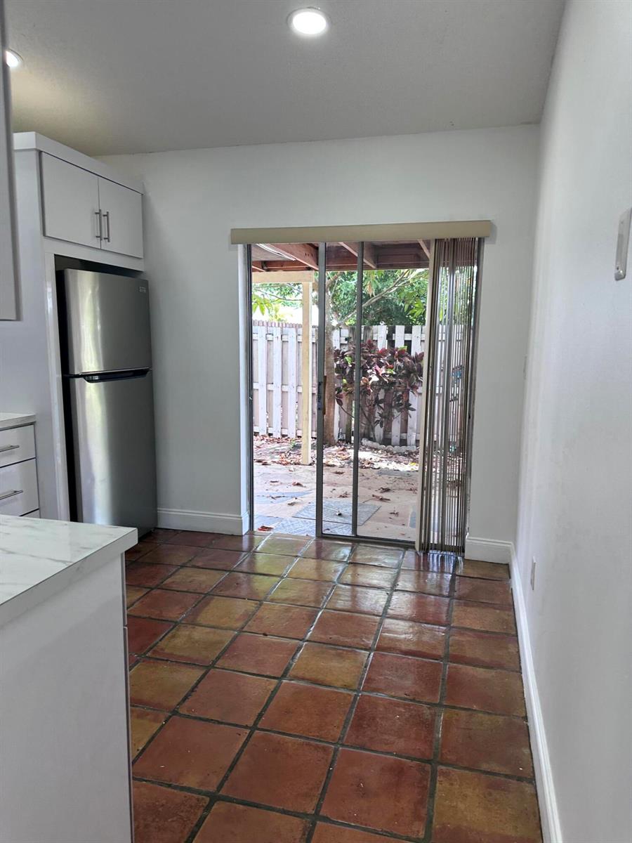 A kitchen with terracotta tile flooring and a sliding glass door leading to a patio — 19823 NW 64th Place, Hialeah FL 33015, HIALEAH, FL