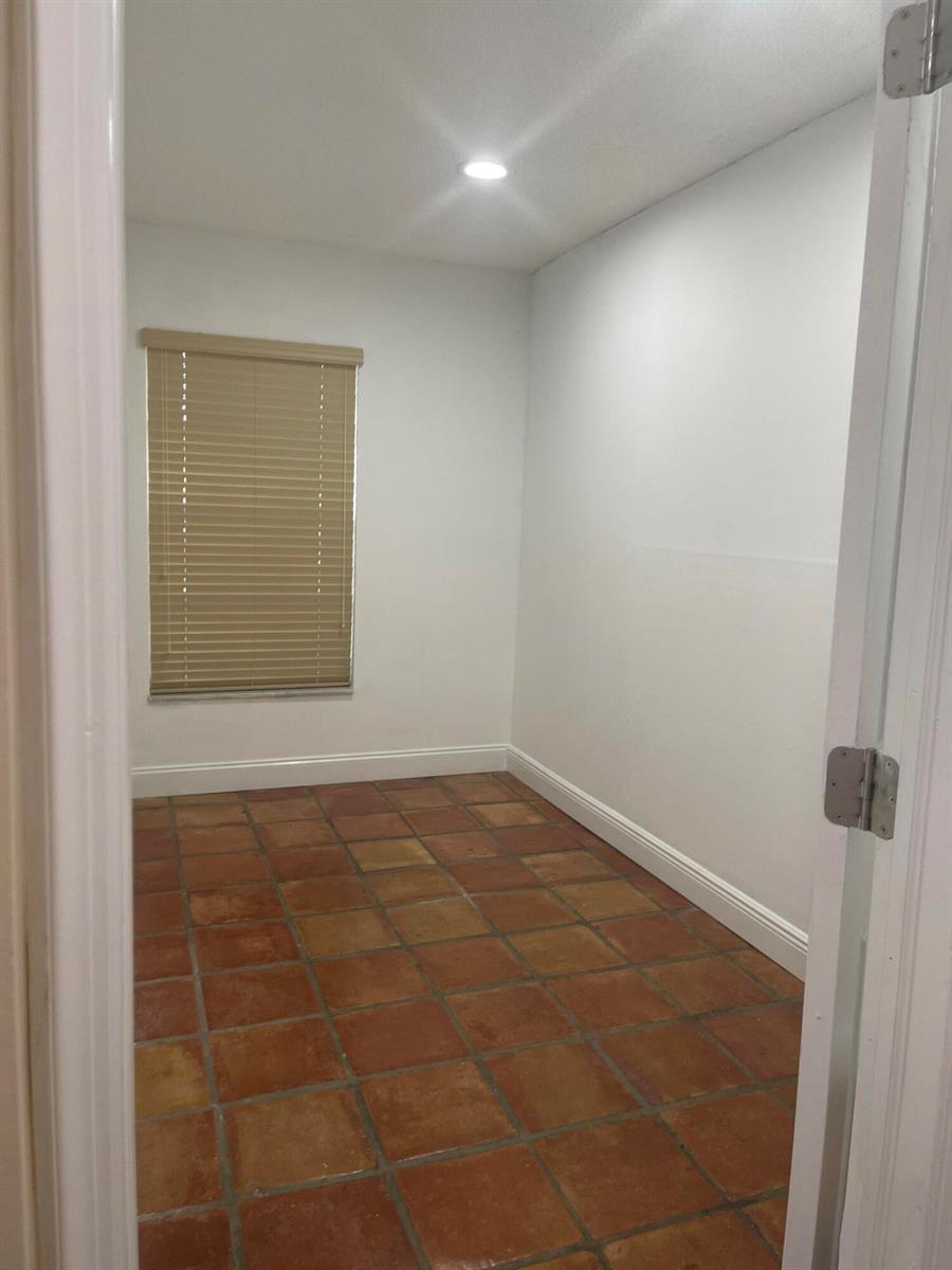 An empty room features white walls, a single window with blinds, and terracotta tile flooring — 19823 NW 64th Place, Hialeah FL 33015, HIALEAH, FL