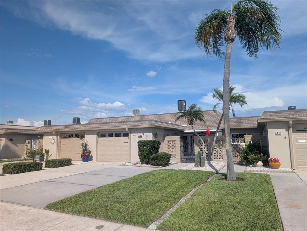 A single-story attached home with a tan exterior, a concrete driveway, and a palm tree — 542 BOCA CIEGA POINT BOULEVARD N UNIT 2108, MADEIRA BEACH, FL