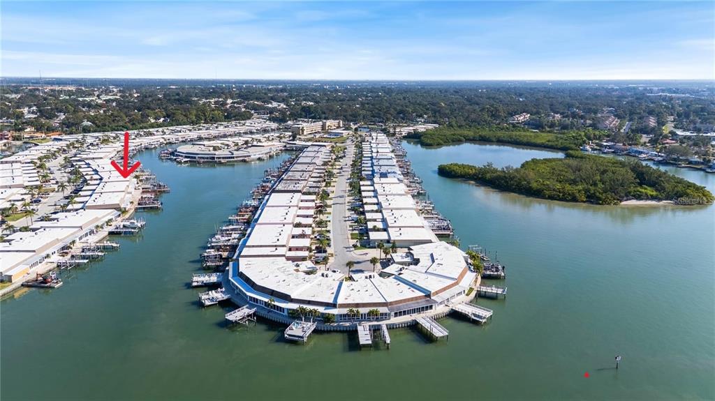 An aerial view shows a waterfront residential complex with boat slips extending into the water — 542 BOCA CIEGA POINT BOULEVARD N UNIT 2108, MADEIRA BEACH, FL