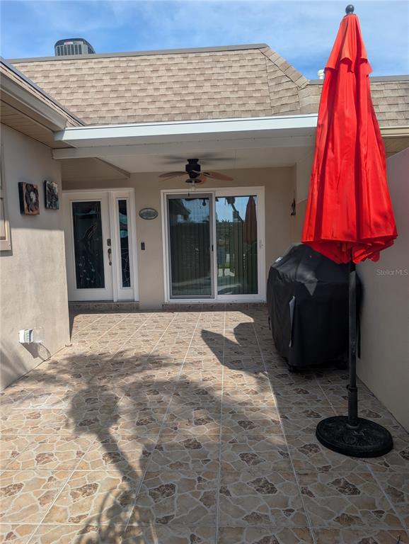 A tiled patio features a covered entryway, a sliding glass door, and a red umbrella — 542 BOCA CIEGA POINT BOULEVARD N UNIT 2108, MADEIRA BEACH, FL