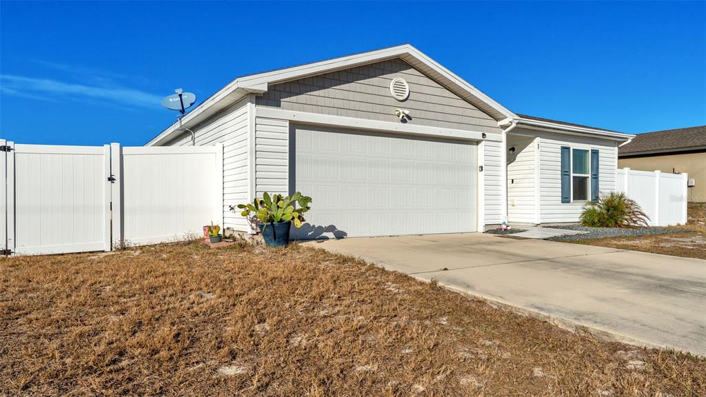 A single-story house with white siding, a two-car garage, and a white vinyl fence — 1 REDWOOD COURT, KISSIMMEE, FL