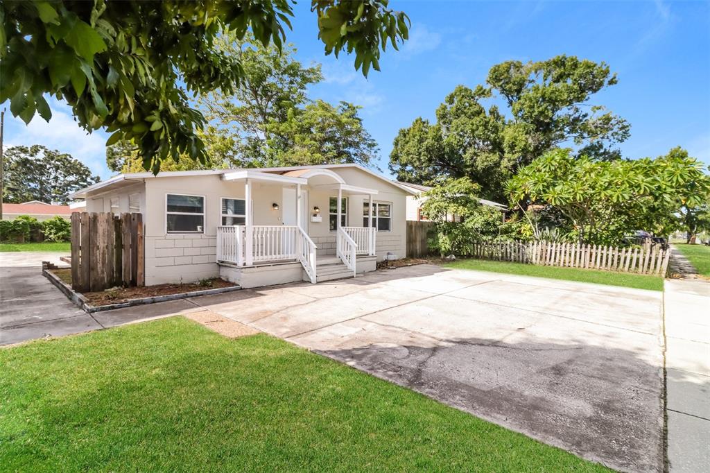 A single-story house with a concrete driveway, white porch railings, and a wooden fence — 2626 15TH AVENUE N, ST PETERSBURG, FL