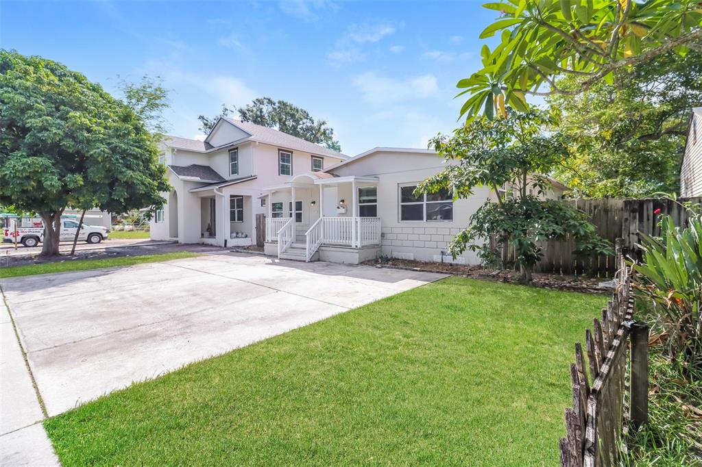 A two-story house and a single-story addition sit beside a concrete driveway and lawn — 2626 15TH AVENUE N, ST PETERSBURG, FL
