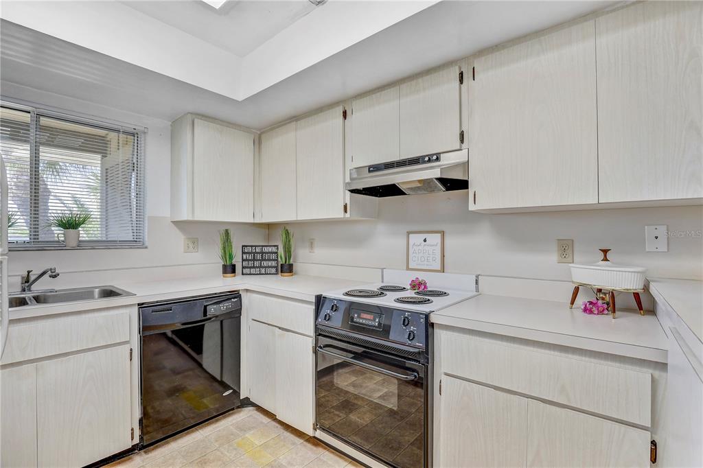 A kitchen features light wood-grain cabinets, white countertops, a dishwasher, and a white electric range — 6400 FLOTILLA DRIVE UNIT 15, HOLMES BEACH, FL