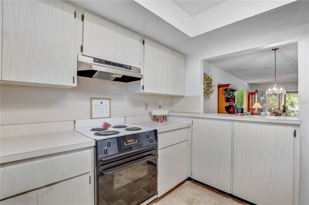 A kitchen features white cabinets, a black electric range, and a pass-through window — 6400 FLOTILLA DRIVE UNIT 15, HOLMES BEACH, FL