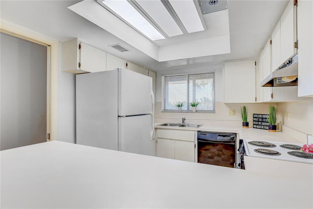 A kitchen features white cabinets, white appliances, a double sink, and a breakfast bar — 6400 FLOTILLA DRIVE UNIT 15, HOLMES BEACH, FL