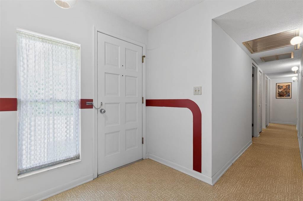 An interior entryway features beige carpeting, white walls with red accents, and a white door — 9603 SW 17TH AVENUE, GAINESVILLE, FL