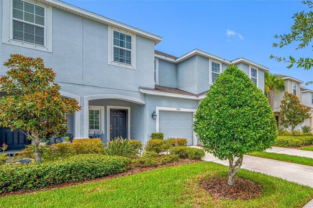 A two-story light blue townhouse with a garage, front door, and manicured landscaping — 7932 EVERGREEN CREEK COURT, RIVERVIEW, FL