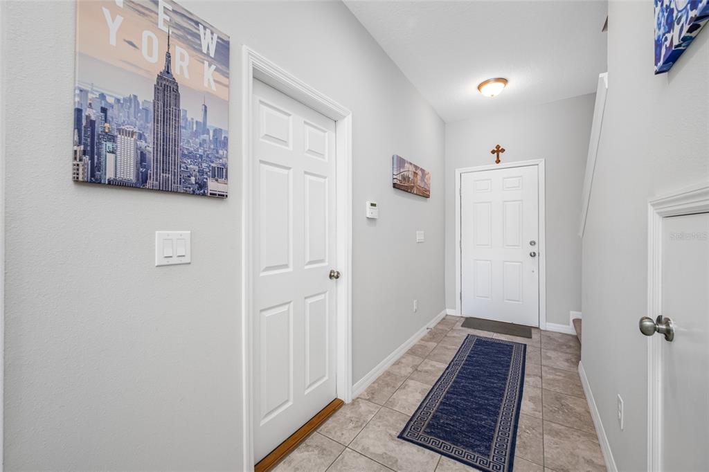 An entryway features light gray walls, tile flooring, a white door, and wall art — 7932 EVERGREEN CREEK COURT, RIVERVIEW, FL