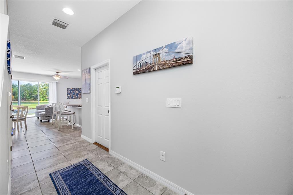 A tiled entryway leads into an open-concept living area with a kitchen island and seating — 7932 EVERGREEN CREEK COURT, RIVERVIEW, FL