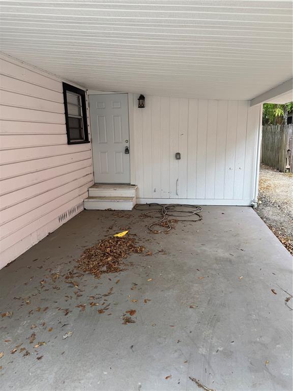 A covered concrete patio area features a white door, pink siding, and a garden hose — 2016 E CLIFTON STREET UNIT B, TAMPA, FL
