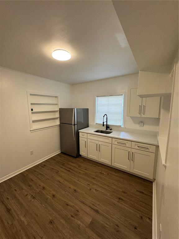 A kitchen features white cabinets, a stainless steel refrigerator, a sink, and wood-look flooring — 2016 E CLIFTON STREET UNIT B, TAMPA, FL
