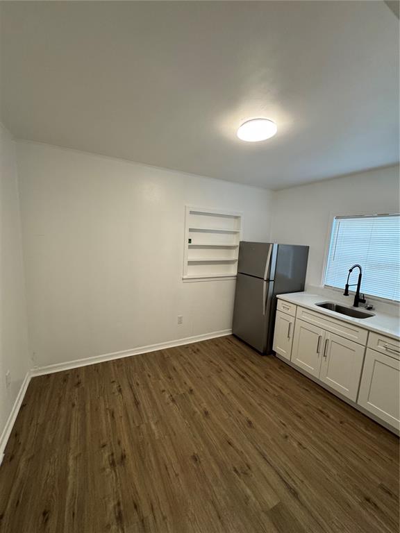 A kitchen features white cabinets, a stainless steel refrigerator, wood-look flooring, and built-in wall shelves — 2016 E CLIFTON STREET UNIT B, TAMPA, FL