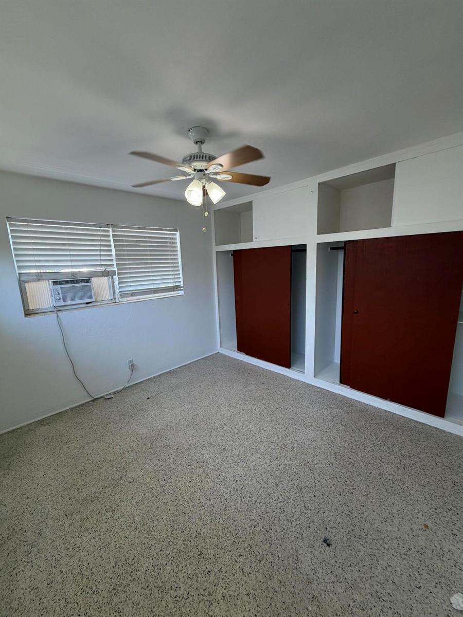 A bedroom features a ceiling fan, carpeted flooring, a window air conditioner, and built-in closets — WEST PALM BEACH, FL