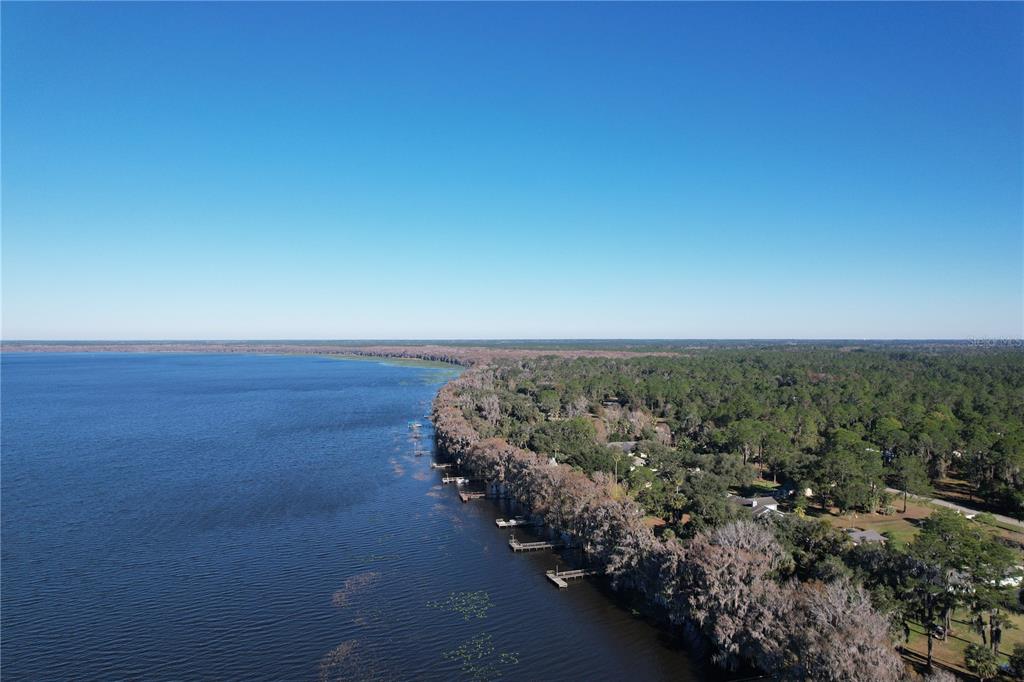 An aerial view shows a lake shoreline with several wooden docks extending into the water — 13919 SE 202ND TERRACE, HAWTHORNE, FL
