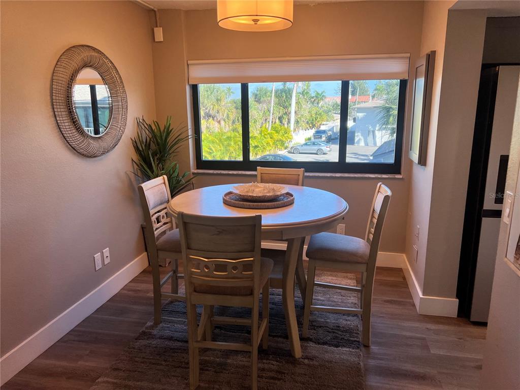 A dining area features a round table with four chairs, a mirror, and a window — 1001 POINT OF ROCKS ROAD UNIT 208, SARASOTA, FL