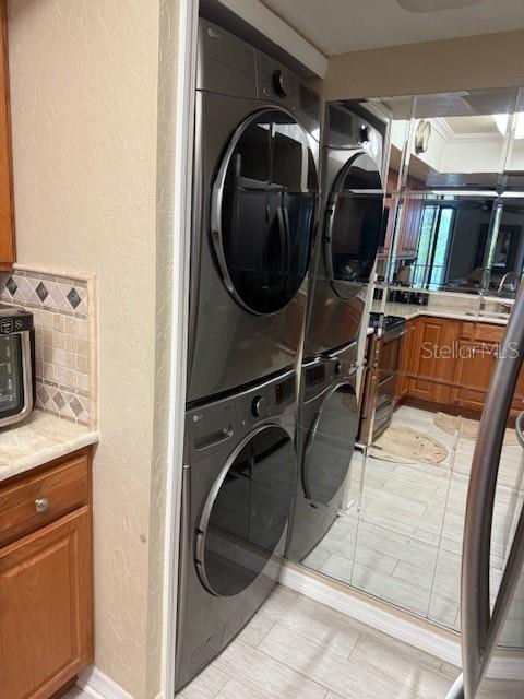A stacked washer and dryer unit is positioned next to a mirrored wall in a kitchen — 25188 MARION AVENUE UNIT D104, PUNTA GORDA, FL