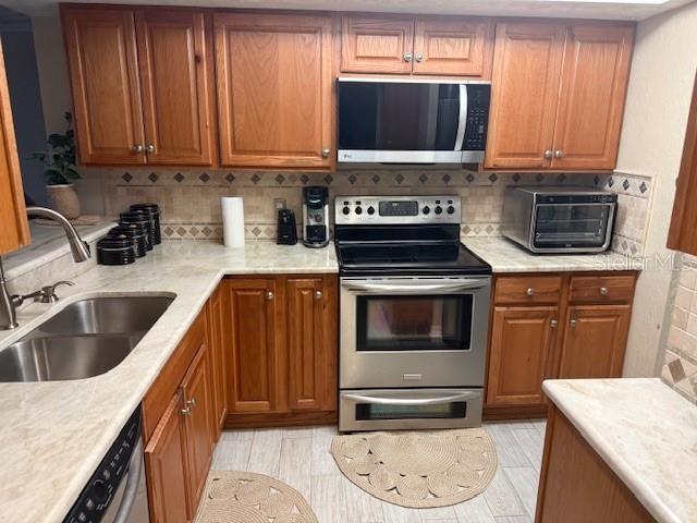 A kitchen features wood cabinets, stainless steel appliances, and light-colored countertops — 25188 MARION AVENUE UNIT D104, PUNTA GORDA, FL