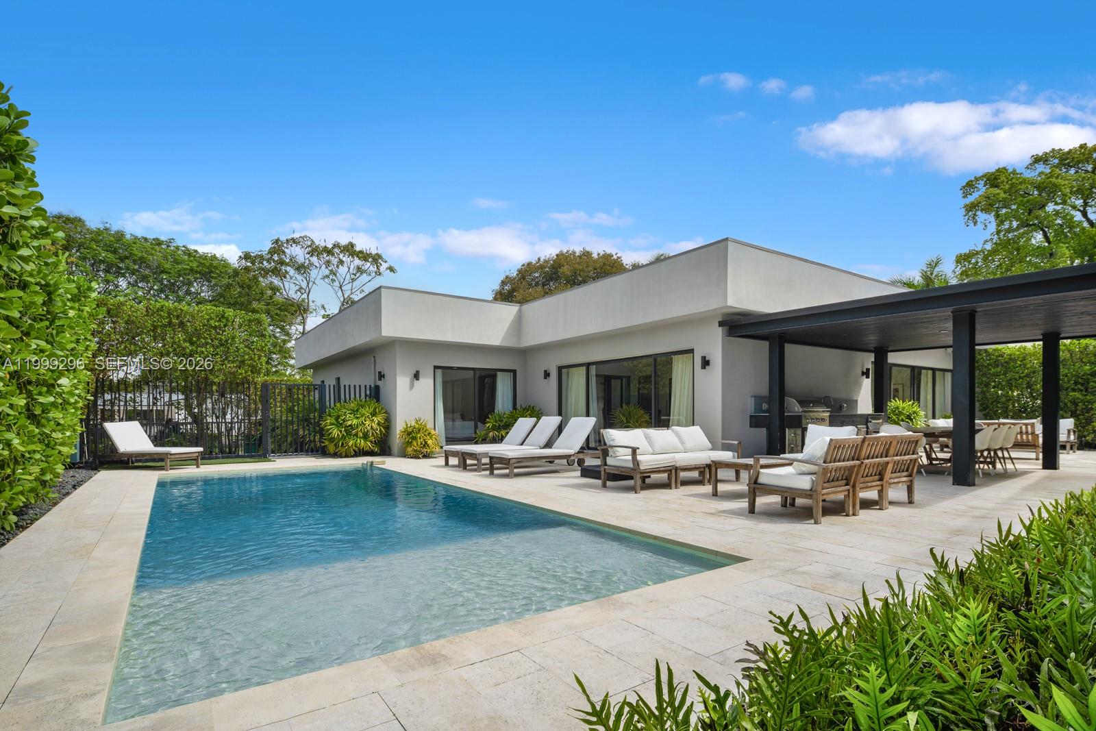 A modern house exterior features a swimming pool, patio furniture, and a covered outdoor kitchen — 70 Samana Dr, Miami FL 33133, MIAMI, FL