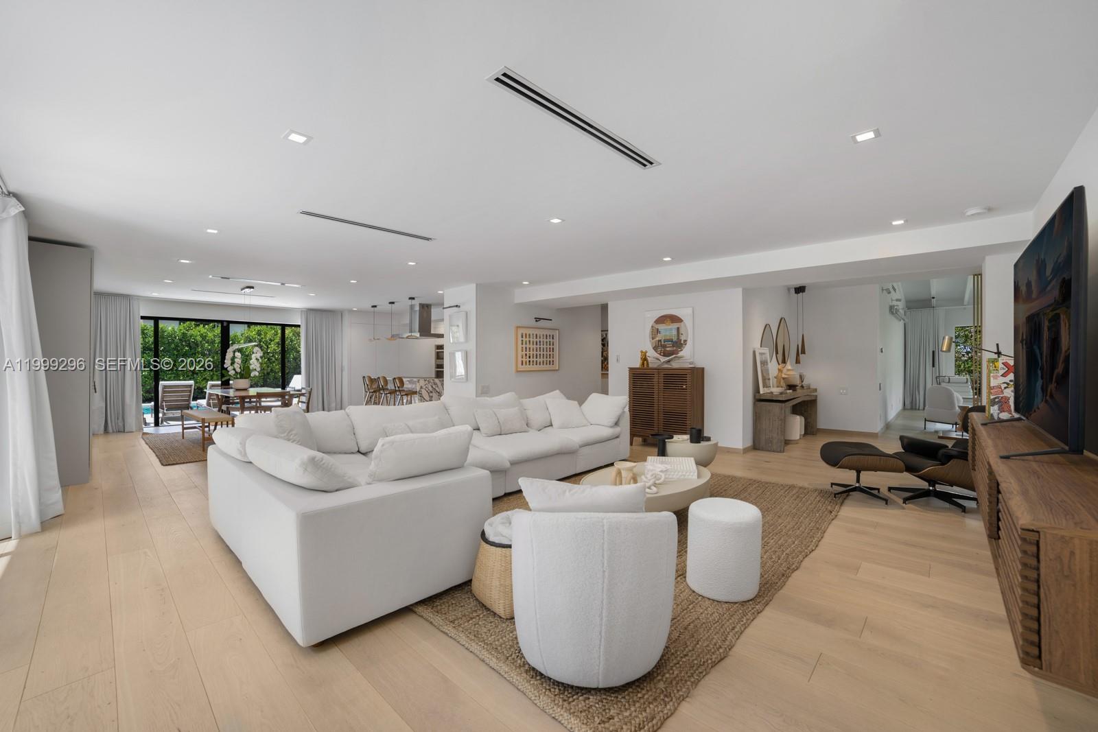 A modern, open-concept living room features a large white sectional, light wood floors, and recessed lighting — 70 Samana Dr, Miami FL 33133, MIAMI, FL