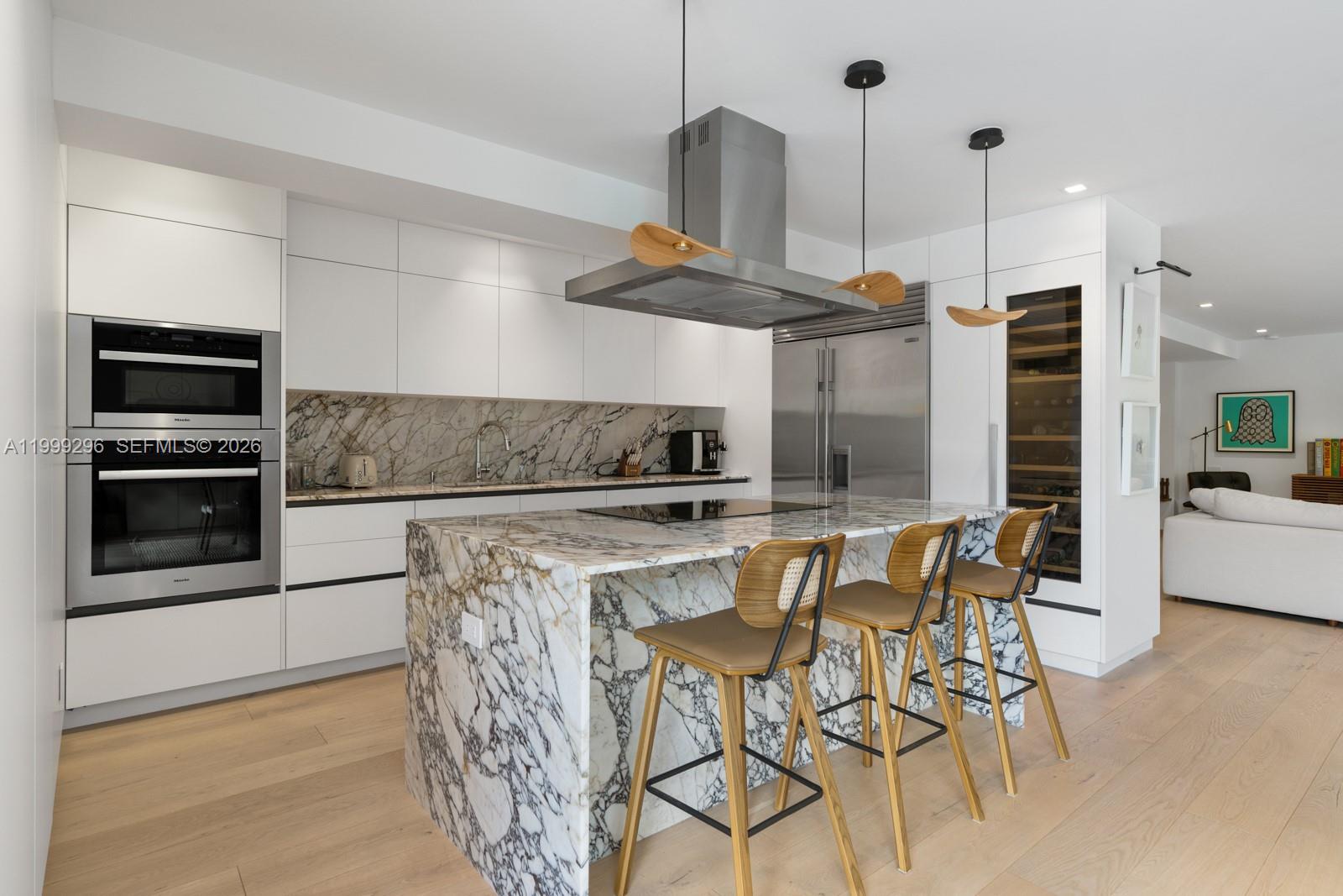 A modern kitchen features a marble waterfall island, white cabinetry, and stainless steel appliances — 70 Samana Dr, Miami FL 33133, MIAMI, FL