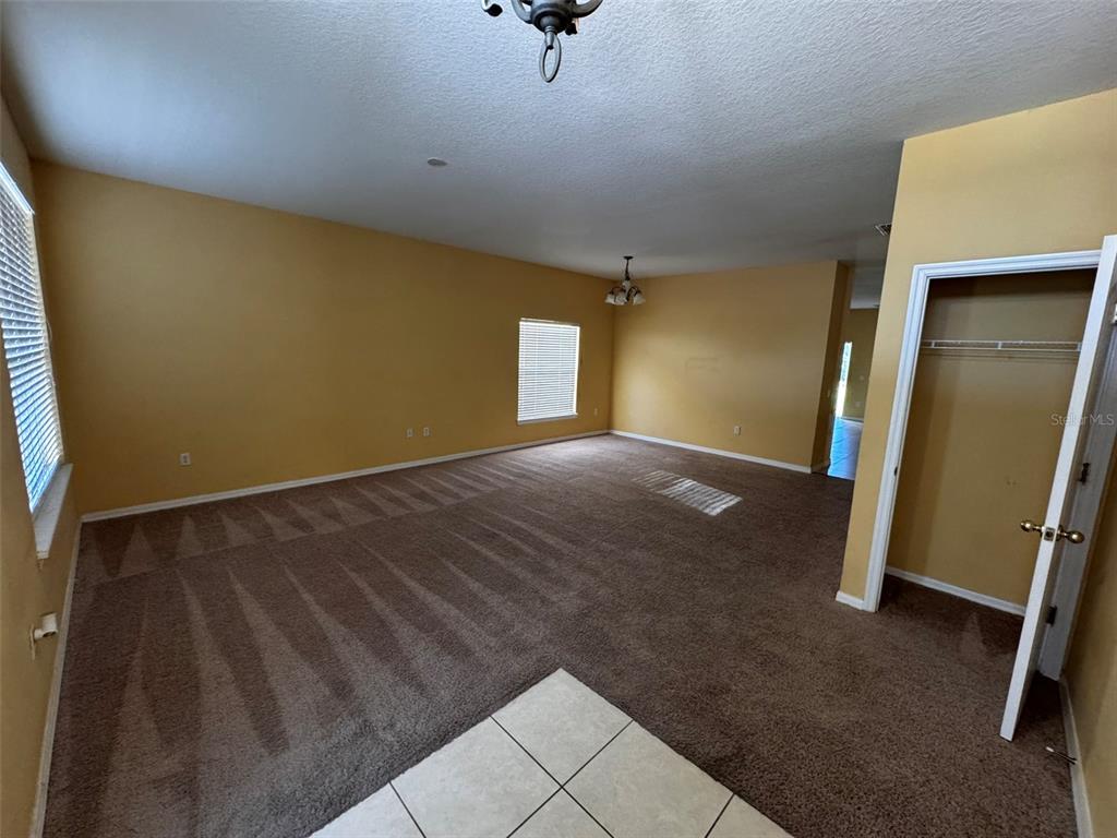 An empty room features tan walls, brown carpeting, and a closet with an open door — 1111 HACIENDA CIRCLE, KISSIMMEE, FL