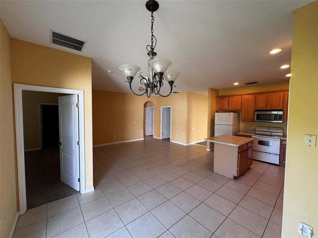 An open-concept kitchen and dining area features tile flooring, wood cabinets, and a central island — 1111 HACIENDA CIRCLE, KISSIMMEE, FL