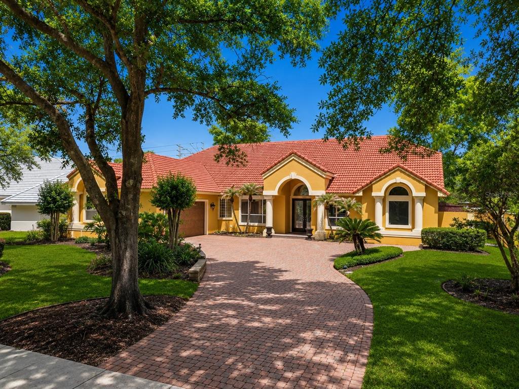 A yellow single-story house with a red tile roof and a brick paver driveway — 7407 PARK SPRINGS CIRCLE, ORLANDO, FL