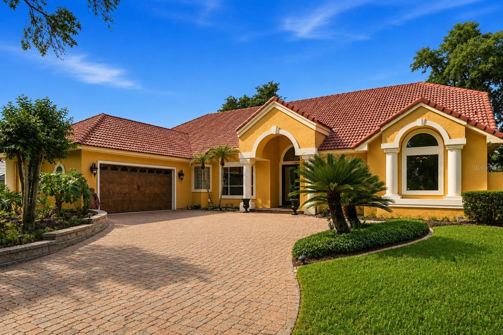 A yellow single-story house with a red tile roof and a paved circular driveway — 7407 PARK SPRINGS CIRCLE, ORLANDO, FL