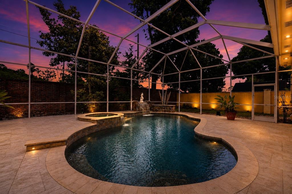 A screened-in pool area features a stone-tiled deck, a hot tub, and a water feature — 7407 PARK SPRINGS CIRCLE, ORLANDO, FL