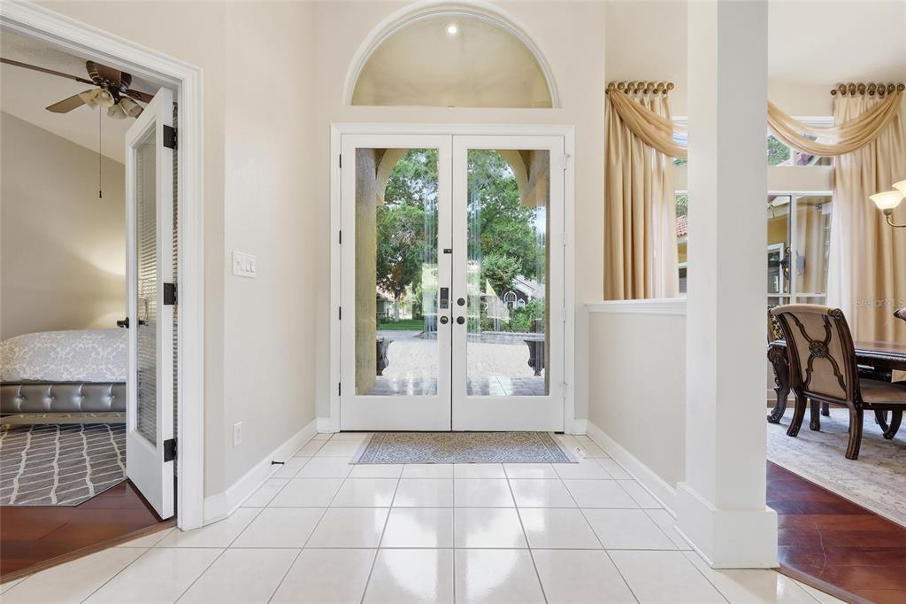 A bright entryway with white tile floors, double glass front doors, and an arched transom window — 7407 PARK SPRINGS CIRCLE, ORLANDO, FL