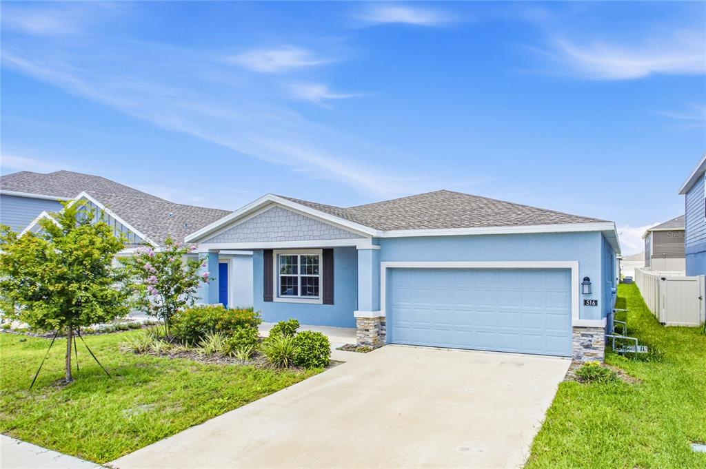 A light blue single-story house features a two-car garage and a front porch — 516 REGGIE ROAD, WINTER HAVEN, FL