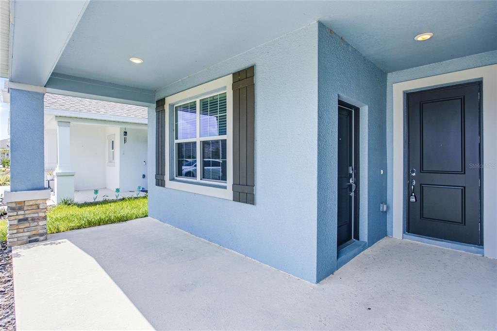 A light blue house exterior features a covered porch, a window with shutters, and doors — 516 REGGIE ROAD, WINTER HAVEN, FL