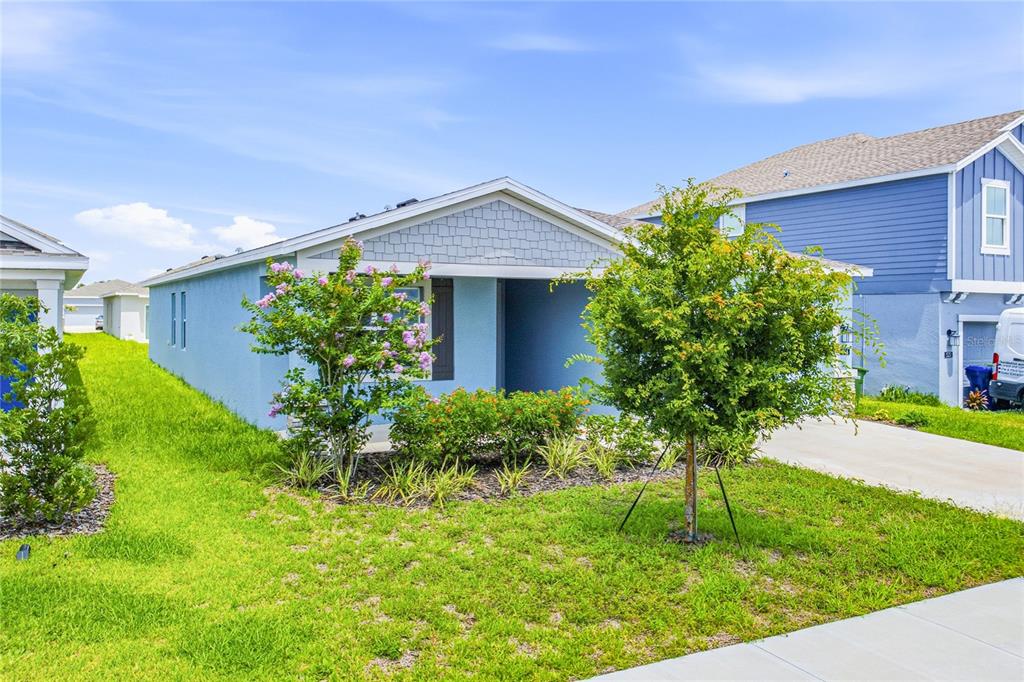 A light blue single-story house with a front porch, landscaping, and a driveway — 516 REGGIE ROAD, WINTER HAVEN, FL