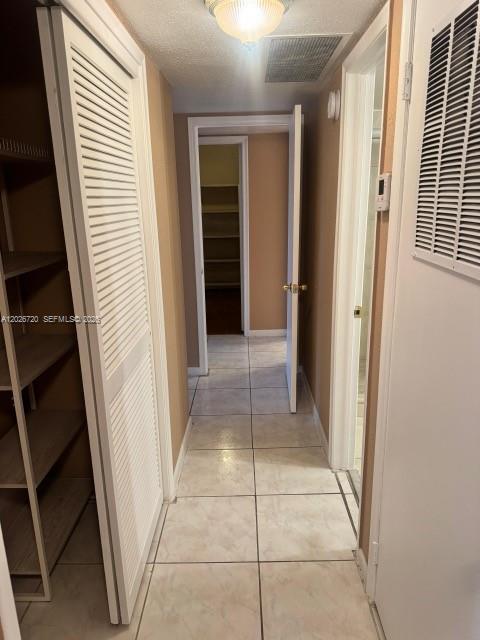 A hallway with tiled floors leads to an open doorway revealing a walk-in closet — 3301 Spanish Moss Ter # 803, Lauderhill FL 33319, LAUDERHILL, FL