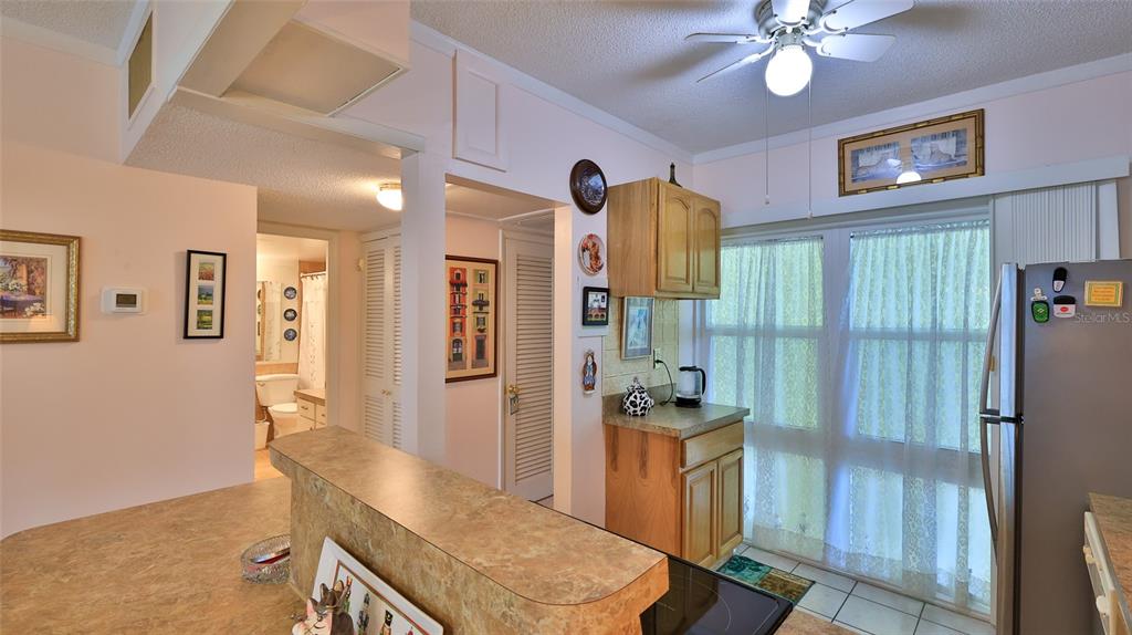 A kitchen with light-colored walls, wood cabinets, a breakfast bar, and a sliding glass door — 717 S BEACH STREET UNIT 205C, DAYTONA BEACH, FL