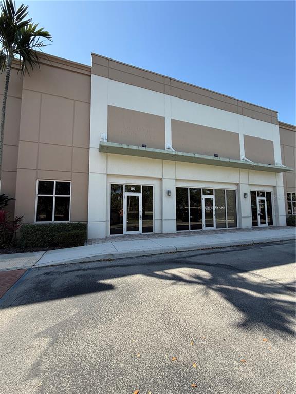 The exterior of a commercial building features tan and white walls with glass entry doors — 1000 STINSON WAY, WEST PALM BEACH, FL