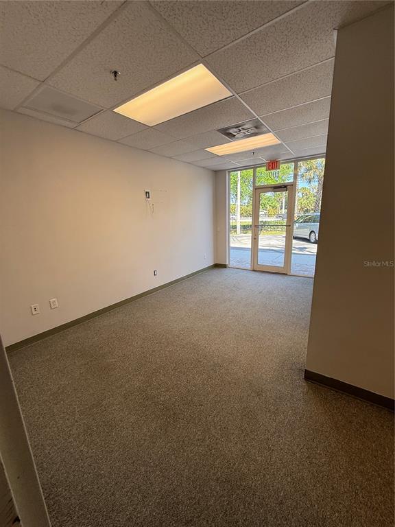 An empty office space with beige carpet, white walls, drop ceiling, and a glass door — 1000 STINSON WAY, WEST PALM BEACH, FL