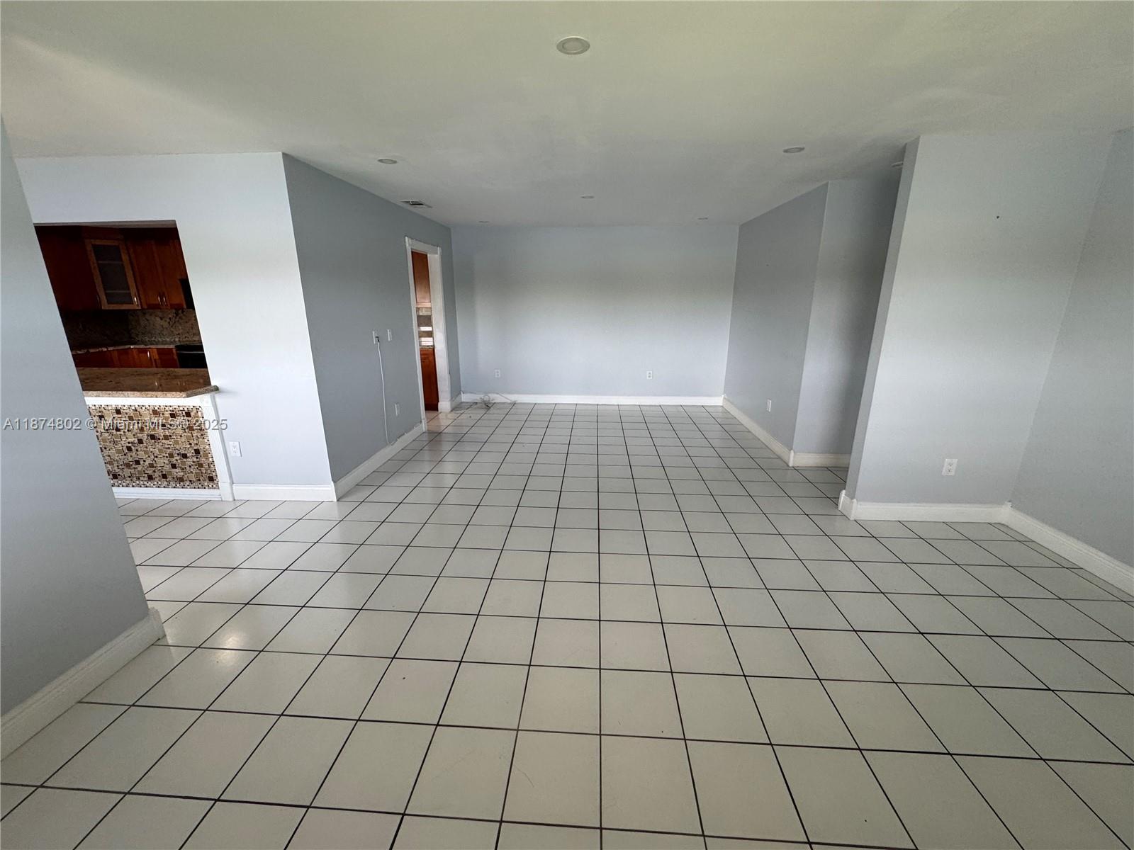 An empty room with light blue walls and white tiled floors features a kitchen pass-through — 13261 SW 17th Ln # 5, Miami FL 33175, MIAMI, FL