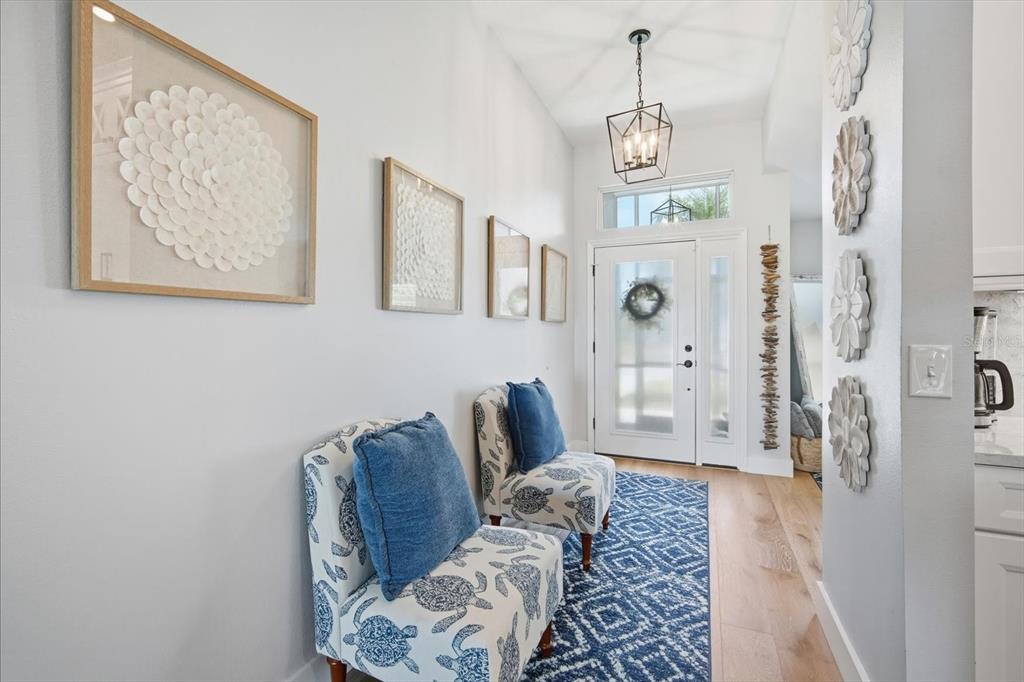 A bright entryway features two patterned chairs, a blue rug, and wall-mounted decorative art — 4844 14TH AVENUE E, BRADENTON, FL